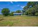 Exterior shot of a blue home with a red front door, blue skies, and surrounding trees at 11015 S County Road 39, Lithia, FL 33547