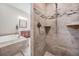 Elegant bathroom featuring a walk-in shower with decorative tiles, a soaking tub, and a wooden vanity at 1119 Hounds Run, Safety Harbor, FL 34695