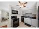 Bright kitchen with black appliances, gray cabinets, ceiling fan, and an adjacent sitting area at 1120 45Th N St, St Petersburg, FL 33713