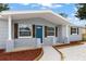 Inviting front porch with stone pillars, rustic shutters, and a vibrant blue front door at 1427 Gerard Ln, Holiday, FL 34690