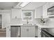Bright kitchen boasts white cabinets, stainless steel dishwasher, and elegant countertops at 1427 Gerard Ln, Holiday, FL 34690