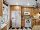 Kitchen with wooden cabinets, white appliances, and stylish black and white tile floors at 1702 Cordova Green, Seminole, FL 33777