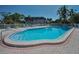 Community pool with blue water surrounded by lounge chairs and palm trees in a tropical community at 1702 Cordova Green, Seminole, FL 33777