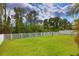 Spacious backyard with tall trees beyond the white picket fence at 2463 Carnation Ct, North Port, FL 34289