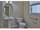 Cozy half bathroom features pedestal sink, toilet and window at 2463 Carnation Ct, North Port, FL 34289