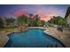 Tranquil backyard pool oasis with rock waterfall features and lush landscaping at dusk at 2613 N Dundee St, Tampa, FL 33629