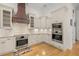 Modern kitchen featuring stainless steel appliances, a custom range hood, and white cabinetry at 2613 N Dundee St, Tampa, FL 33629