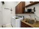 Bright laundry room with granite counters, wood cabinets, sink, and updated washer and dryer at 2613 N Dundee St, Tampa, FL 33629