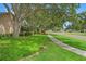 Well-maintained landscaping adorns the expansive front yard with mature trees and lush greenery at 3320 Pattie Pl, Palm Harbor, FL 34685