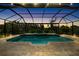 The dusk picture features a screened in pool, complete with landscape lighting and lush surrounding trees at 5313 Sanderling Ridge Dr, Lithia, FL 33547