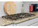 Close-up of a kitchen stove top featuring granite countertops and white cabinets at 5313 Sanderling Ridge Dr, Lithia, FL 33547