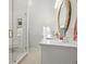 Bathroom featuring white vanity with quartz countertops, a round mirror, and tiled walk-in shower at 621 Duchess Blvd, Dunedin, FL 34698