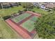 Aerial view of tennis courts surrounded by lush green grass and mature trees at 621 Duchess Blvd, Dunedin, FL 34698