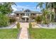 Expansive backyard with a lush lawn, tropical plants, a tiki hut, and a sparkling pool with lounge chairs at 633 Soundview Dr, Palm Harbor, FL 34683