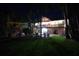 Stunning backyard view featuring a well-lit deck, a pool, tropical plants and an inviting tiki hut at 633 Soundview Dr, Palm Harbor, FL 34683