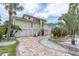 Inviting yellow home with two-car garage, white staircase, and lush tropical landscaping at 633 Soundview Dr, Palm Harbor, FL 34683