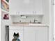 Well-lit laundry area with overhead storage and under counter cabinet at 633 Soundview Dr, Palm Harbor, FL 34683