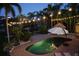 Backyard pool illuminated at night, surrounded by tropical landscaping and a charming tiki hut at 633 Soundview Dr, Palm Harbor, FL 34683