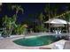 Backyard pool with lush landscaping, a tiki hut, an umbrella, and elegant patio furniture at 633 Soundview Dr, Palm Harbor, FL 34683