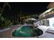 Inviting backyard pool area with a tiki hut, poolside seating, and lush tropical foliage at night at 633 Soundview Dr, Palm Harbor, FL 34683