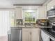Galley kitchen features stainless steel appliances, granite counters, a mosaic backsplash, and lots of natural light at 6627 Main St, New Port Richey, FL 34653