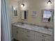 Dual sink bathroom with granite countertop, decorative mirrors, and modern lighting fixtures at 9035 37Th N St, Pinellas Park, FL 33782