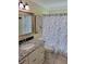 Bright bathroom features a granite countertop vanity and a tub with a decorative floral shower curtain at 9035 37Th N St, Pinellas Park, FL 33782