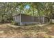 Quaint gray home with verdant foliage, set back from the road, offers a peaceful setting at 9132 Mango St, New Port Richey, FL 34654