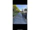 Long black asphalt driveway gated with metal and greenery surrounding the sides at 9900 Ideal Ln, Hudson, FL 34667