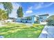 Relaxing backyard with new turf and rock landscaping, patio seating, and bright blue house at 1015 Spindle Palm Way, Apollo Beach, FL 33572