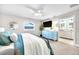 Cozy bedroom featuring a blue dresser, television, ceiling fan, and ensuite bathroom at 1015 Spindle Palm Way, Apollo Beach, FL 33572