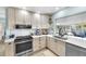 Modern kitchen with white cabinetry, stone countertops, stainless steel appliances, and views into the living room at 1015 Spindle Palm Way, Apollo Beach, FL 33572