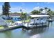 Aerial view of a bright blue waterfront property, boat dock, and lush landscaping at 1015 Spindle Palm Way, Apollo Beach, FL 33572