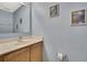 Half bathroom featuring a single sink vanity, framed mirror, and light blue walls adorned with nautical-themed art at 11257 Persimmon Ave, Weeki Wachee, FL 34614