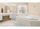Bright bathroom featuring a soaking tub, dual vanity, and a large window at 11284 Hickory Ridge Ct, Spring Hill, FL 34609