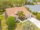 Aerial view of a tan single-Gathering home with a brown roof, well-manicured lawn, and mature landscaping at 11284 Hickory Ridge Ct, Spring Hill, FL 34609