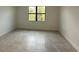 A bedroom features neutral tile flooring and a window with views of lush greenery at 17122 Moonflower Dr, Venice, FL 34293