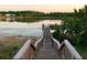 Scenic view of a wooden dock extending into a calm lake surrounded by lush greenery and distant houses at 20053 Heritage Point Dr, Tampa, FL 33647