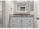 Bathroom vanity featuring granite countertop, mirror and white cabinetry at 204 Cactusflower Ln, Sun City Center, FL 33573