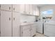 Bright laundry room with tile floor, white cabinets, sink, washer and dryer at 204 Cactusflower Ln, Sun City Center, FL 33573