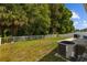 Spacious backyard with lush greenery, white fence, patio area, and modern AC unit, blending comfort with nature at 25304 Lexington Oaks Blvd, Wesley Chapel, FL 33544