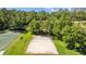 Aerial view of a sand volleyball court next to a basketball court in a lush, green recreational area at 25304 Lexington Oaks Blvd, Wesley Chapel, FL 33544