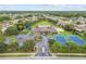 Aerial view of a community with a pool, tennis courts, parking, and playground amid homes and green spaces at 2611 Eagle Crest Ct, Holiday, FL 34691