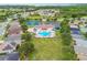 Aerial view of a community showcasing a pool, tennis courts, playground, and homes amidst lush green spaces at 2611 Eagle Crest Ct, Holiday, FL 34691