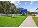 Well-maintained community playground with swings, slide, and covered play area surrounded by green turf at 2611 Eagle Crest Ct, Holiday, FL 34691