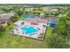 Aerial view of a community pool featuring a spa, ample lounge chairs, and adjacent tennis and volleyball courts at 2611 Eagle Crest Ct, Holiday, FL 34691