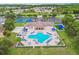 Aerial view of a pool with plenty of lounge chairs, tables, tennis courts, and parking in a community at 2611 Eagle Crest Ct, Holiday, FL 34691