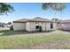 The backyard shows a home with a neutral exterior and a green lawn at 26377 Bertram Rd, Brooksville, FL 34602