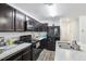 A kitchen showcases dark cabinets, stainless sink, and a full black appliance package at 26377 Bertram Rd, Brooksville, FL 34602