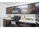 Kitchen featuring dark cabinets, a black appliance package, and light countertops at 26377 Bertram Rd, Brooksville, FL 34602